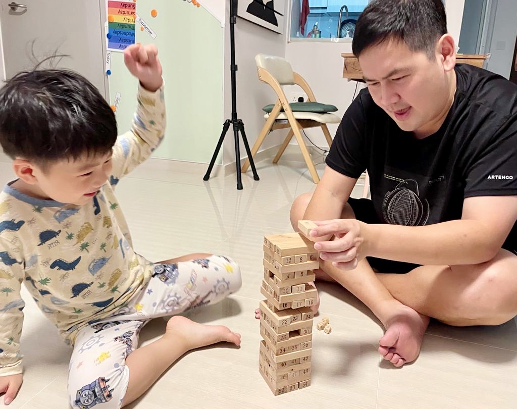 A person and a child playing with blocks Description automatically generated with low confidence