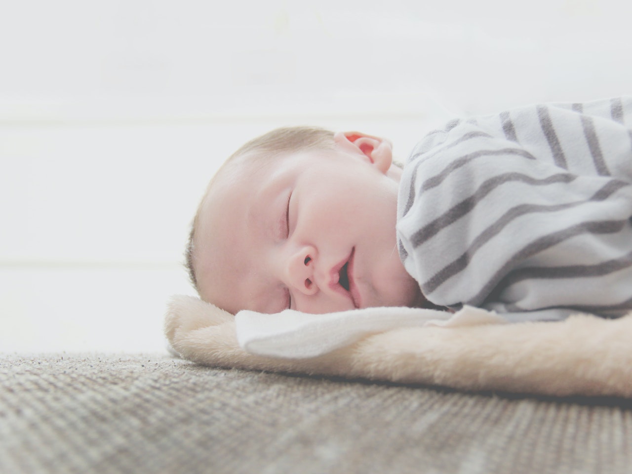 A baby sleeping on a bed Description automatically generated with medium confidence