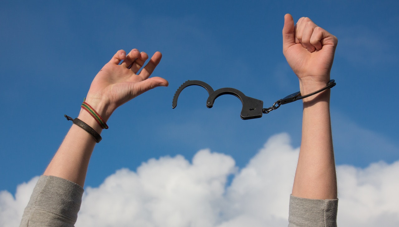 A person's hands with handcuffs
Description automatically generated
